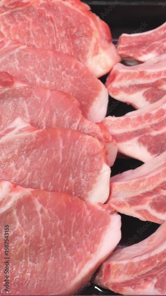 Fresh pork chops are arranged neatly on a black tray, highlighting their marbling and texture, perfect for culinary presentations, recipes, and food photography Fresh pork chops are arranged neatly on a black tray, highlighting their marbling and texture, perfect for culinary presentations, recipes, and food photography