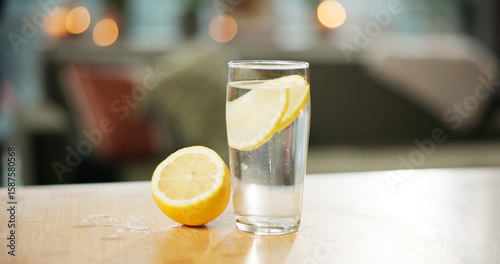 Foto Counter, glass and water with lemon in kitchen for detox, antioxidant or vitamin c for wellness