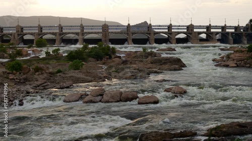 Powerful river flows beneath a historic bridge at sunset mettur dam