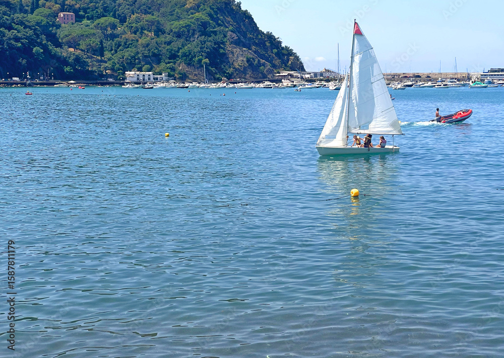 Obraz premium Sestri Levante, Italy - July 15, 2025. Sailboats in sea. Sport and sailing school for teenagers and adults. Nature and vacation in Italy. Leisure and seasons.