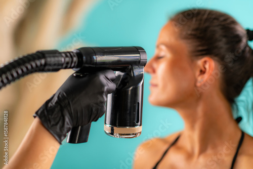 Foto Facial spray tan session in salon, highlighting the mist as it gently coats the woman’s face for a smooth and golden look