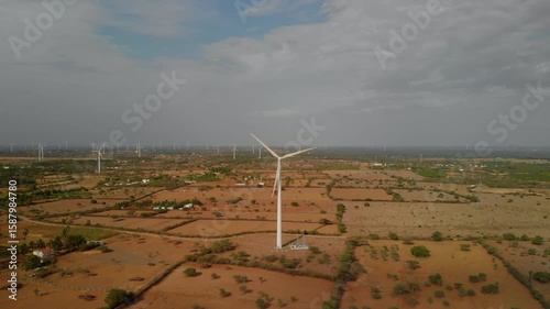 Wind turbine in rural landscape under cloudy sky