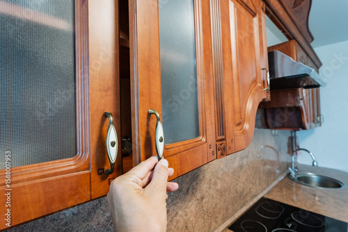 Tableau sur toile A person is in the process of opening a kitchen cabinet door, revealing the cont