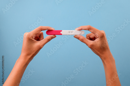 Fotografia Female Hands Holding Pregnancy Test Over Blue Background