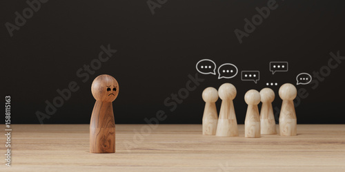 Sad wooden figure excluded from group. Concept of bullying, discrimination, isolation, loneliness, and mental health in society, workplace or school.