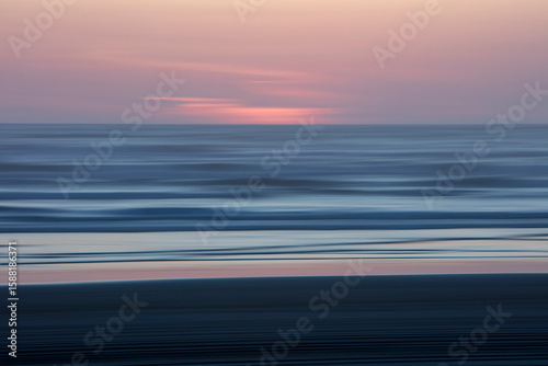 Blurred motion abstract of ocean waves, beach and sky at dusk