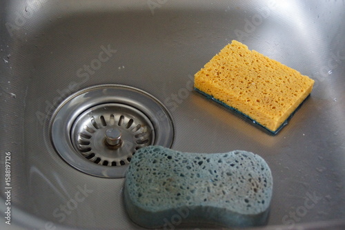 Two sponges lie side by side on a neutral surface, showcasing their contrasting textures and vibrant colors. 