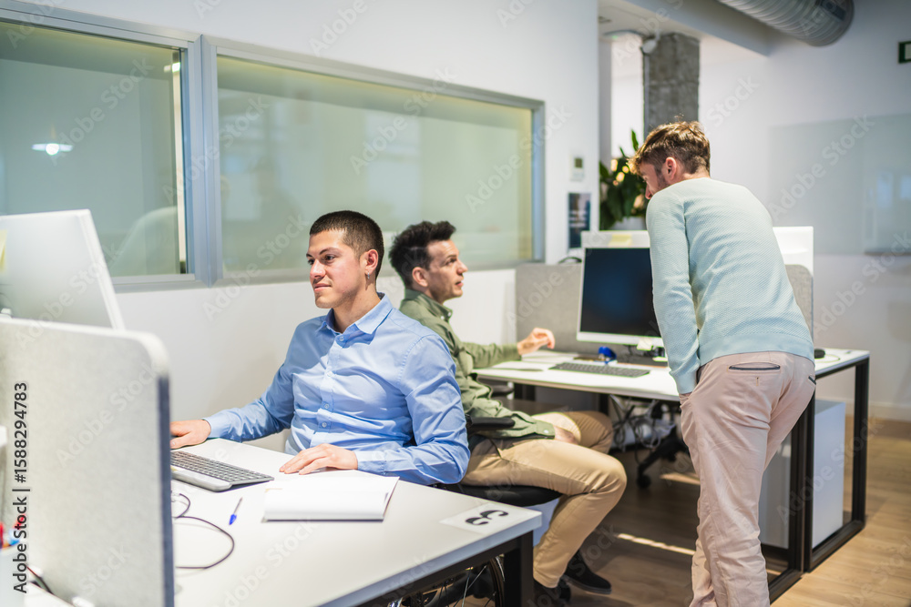 Obraz premium Office workers using desktop computer and collaborating on a project in a modern coworking space