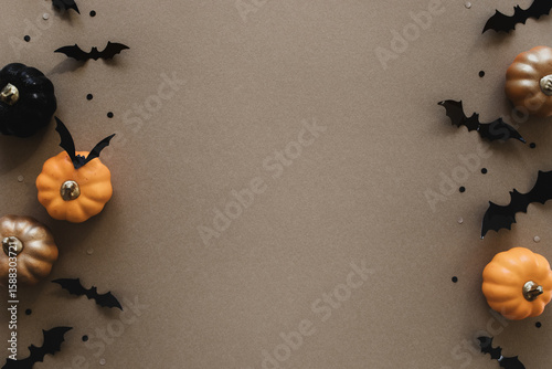 Halloween holiday mockup with party decorations of pumpkins, bats on gold background top view. Happy halloween greeting card in flat lay style.