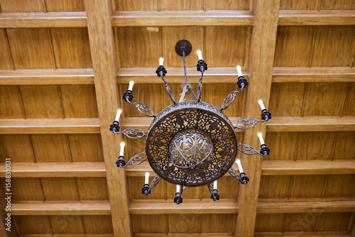 Antique wrought iron chandelier on wooden ceiling