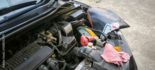 Car engine bay under maintenance with open hood at an auto repair shop.