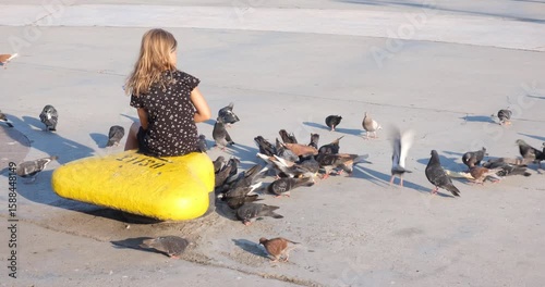 Yalta, Crimea, June 15, 2022. A girl feeds pigeons on the city embankment. The concept of birds, eveA girl feeds pigeons on the city embankment. The concept of birds, everyday urban life. 4K 4096x2160
