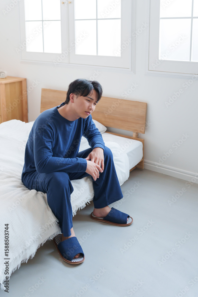Fototapeta premium ベッドで落ち込む男性