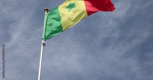 The Senegalese flag is captured in close-up. The flag of Senegal, flying against the blue sky, is the national symbol of Senegal. Great for news. The video is presented in 4K format.