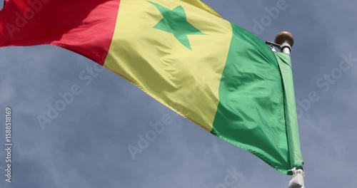 The Senegalese flag is captured in close-up. The flag of Senegal, flying against the blue sky, is the national symbol of Senegal. Great for news. The video is presented in 4K format.