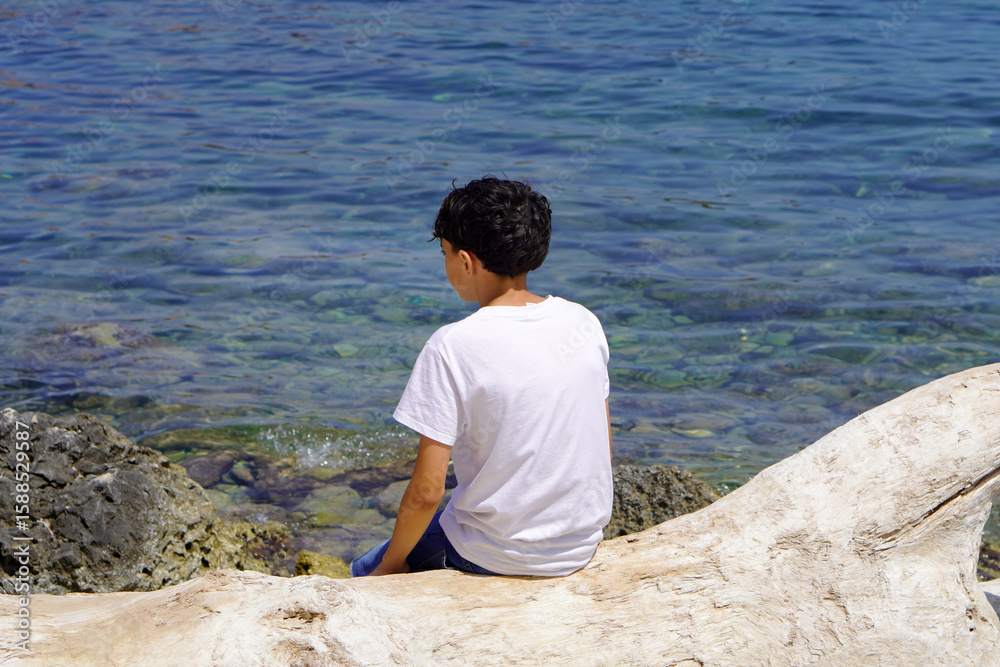vacation concept. preteen child on his back sitting by the shore of a lake or river vacation concept. preteen child on his back sitting by the shore of a lake or river