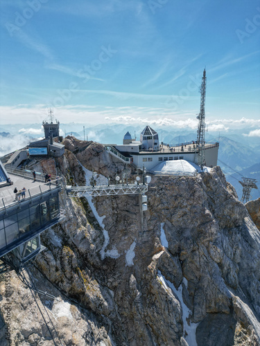 Drone view of the Zugspitze summit, Germany’s highest peak in the Bavarian Alps. The aerial photo captures the mountain station, observation platforms, rugged cliffs, and the breathtaking alpine
