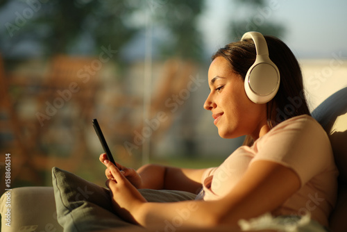 Relaxed woman at home listening audio checking mobile phone
