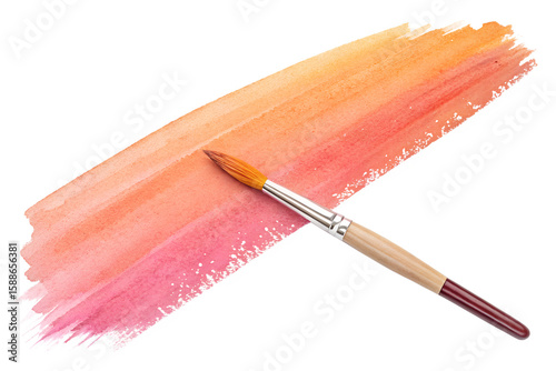 Wooden paintbrush on pink to orange gradient brushstroke, artistic color blend 