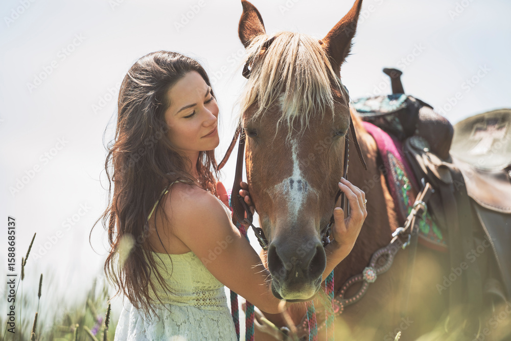 Fototapeta premium woman cowgirl, stands next to her horse in summer season