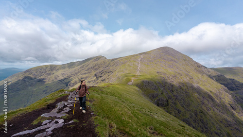 Beautiful landscape of the Kerry Mountains. A female hiker walks along a mountain ridge. Mountain tranquility, fresh air.