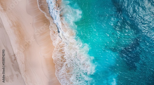 A breathtaking aerial view captures the contrast between soft sandy beach and vibrant turquoise ocean water, showcasing a tropical paradise from a high perspective