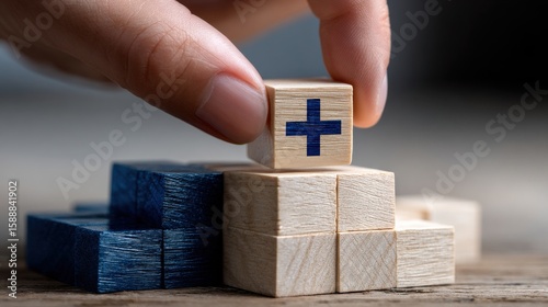 A hand is holding a wooden block with a cross on it