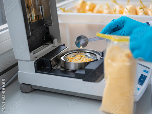 Photos Laboratory technician in blue gloves analyzing yellow food sample using precisio