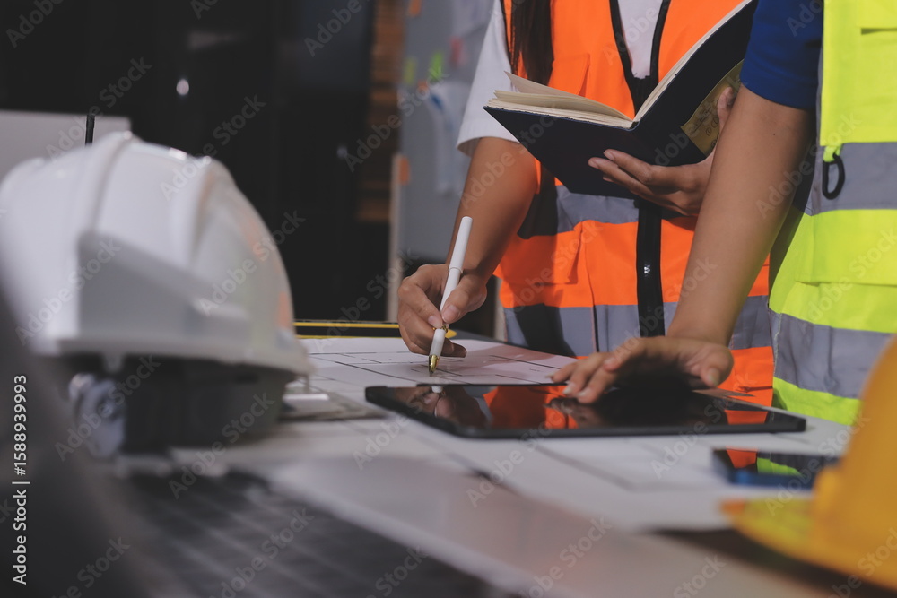 Obraz premium Closeup of team of industrial engineers meeting analyze machinery blueprints consult project on table in manufacturing factory. Working in manufacturing plant or production plant.