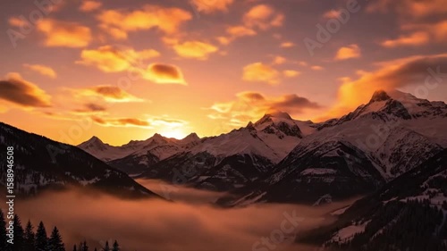 Stunning timelapse of a golden sunset over majestic snow-covered mountains, glowing clouds, and drifting valley fog. A serene and dramatic nature scene.