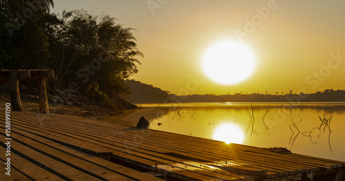 Beautiful sunrise over a small wooden pier and gallons, golden and clear sky, with fog on the freshwater beach of the Várzea das Flores dam, in Contagem, Minas Gerais, Brazil.