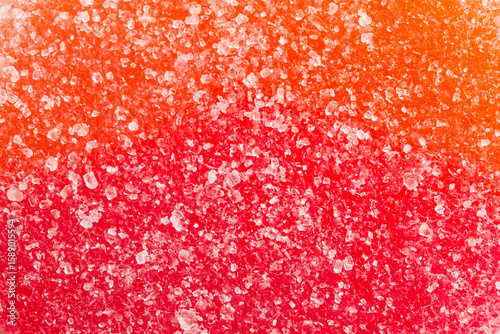 High-detail macro view showcasing sweet sugar granules sprinkled over red‑orange candy, highlighting vivid color contrast and dessert appeal in a bright background. Photo