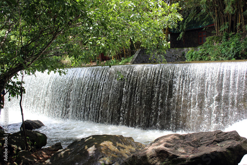 Scenic Waterfall Flowing Over Dam Wall in Forest Setting
