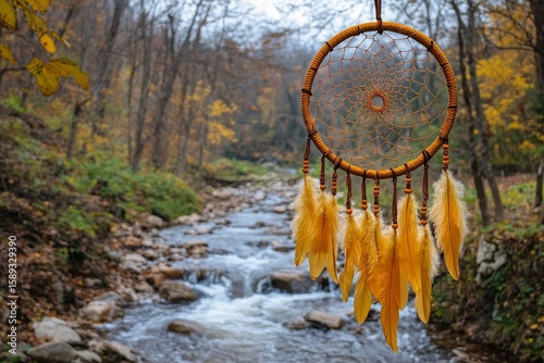 Dreamcatcher Hangs Near a Serene River in Autumn Surrounded by Colorful Trees.