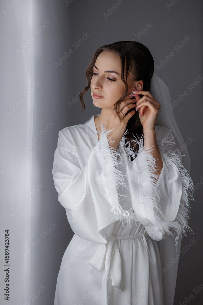 Bride adjusting earrings in a softly lit room with elegant decor before the wedding Bride adjusting earrings in a softly lit room with elegant decor before the wedding