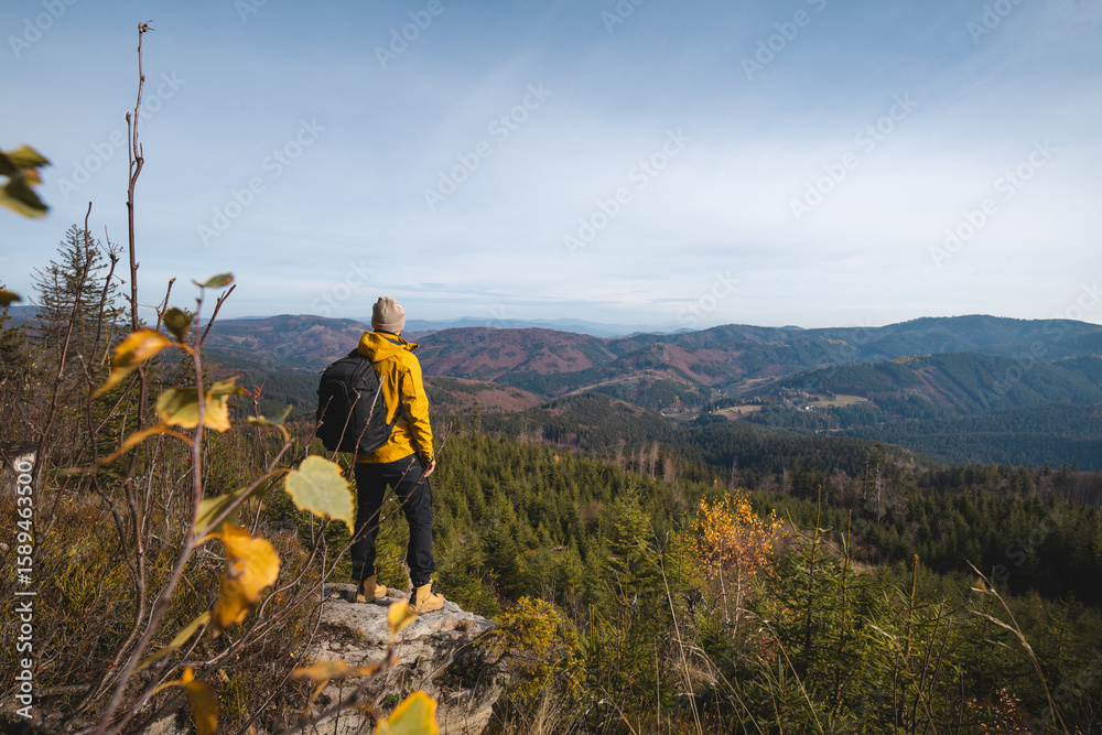 Naklejka premium Man in cozy outfits explores Beskydy mountains in autumn. Scenic forests, sun flares, rustic moments and peaceful views create warm, tranquil outdoor atmosphere