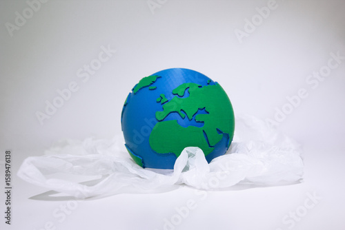 Earth Globe Wrapped in White Plastic Bag. Earth model enclosed in transparent plastic bag symbolizing environmental pollution and planetary protection concerns. Plastic waste problem. Plastic free.
