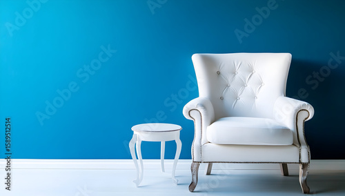 Photo of a white armchair and a small side table against an empty blue wall background