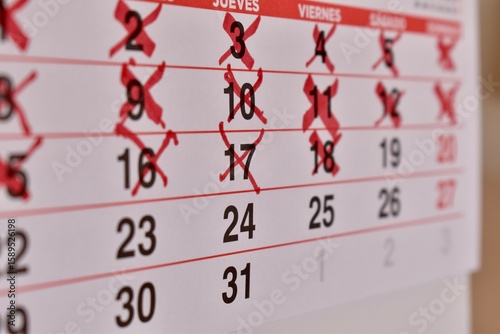 Close-up of Spanish calendar with days marked in red. Represents schedule, deadline, and upcoming events.