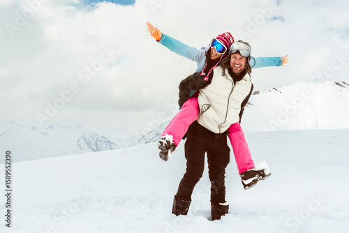 Caucasian happy adult skier couple together piggyback arms up walk together enjoy snowy day freedom in winter mountains ski resort. Winter seasonal holidays vacation white xmas freedom outdoors