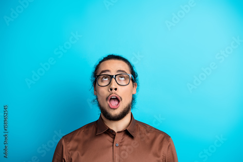 Portrait of a young man with an expressive look in a stylish outfit against a turquoise background