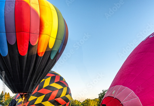 A bunch of hot air balloons are preparing to launch, with one of them being red