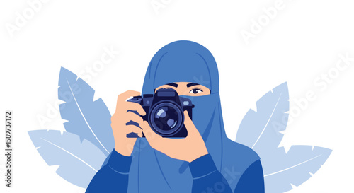 A person wearing a blue hijab and niqab holds a camera and takes a photo surrounded by blue leaves
