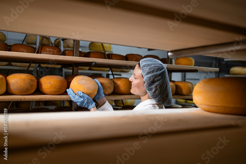 Foto Experienced cheese manufacturer holding parmesan quality cheese in storage room