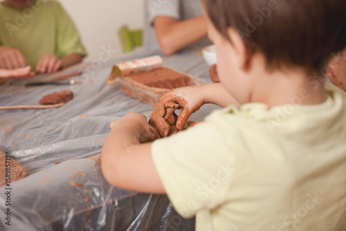 Fotografie Toddler modeling clay during sensory playtime with siblings at home
