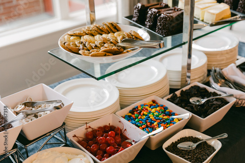 Fototapeta Naklejka Na Ścianę i Meble -  Dessert buffet featuring cookies, candies, and toppings at an indoor gathering during afternoon hours