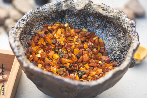 Fototapeta Naklejka Na Ścianę i Meble -  Many small pieces of rough amber of different colours in a ceramic bowl in a street market