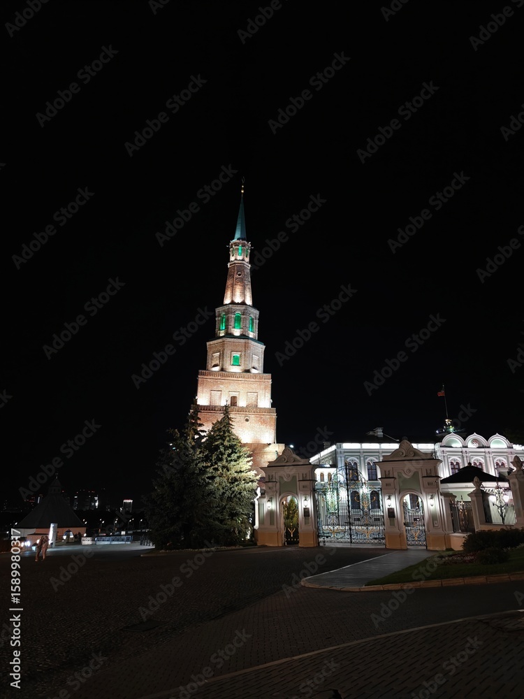 Obraz premium Nighttime view of a historic tower illuminated in green located in a city square