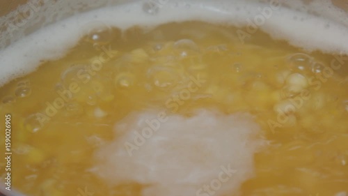 Cooking lentils in a stainless steel pot on a modern kitchen stovetop during the afternoon