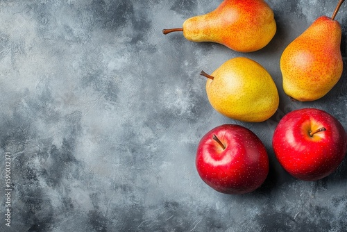 Fresh Fruit Arrangement Featuring Apples and Pears on a Textured Gray Surface.